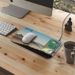 A minimalist mouse pad charging a phone, with a subtle logo in the corner